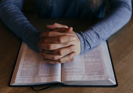 Hands clasped over Bible